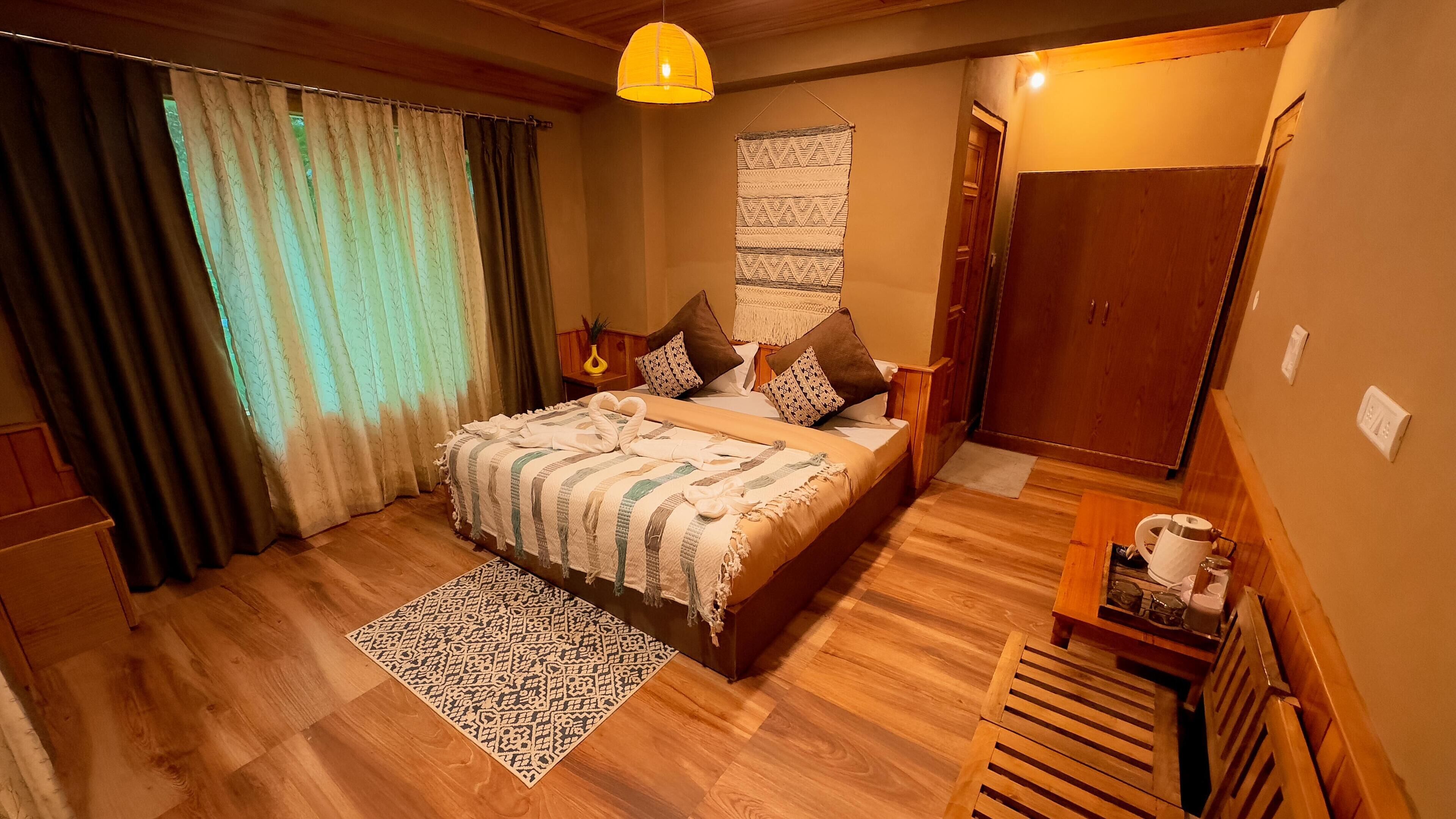 Een slaapkamer met een houten bed, een kamerkleed met een patroon, een hanglamp en een deur met houten kader.