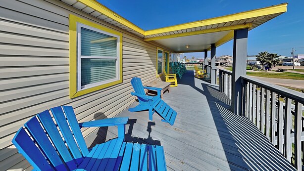 A wooden deck with blue Adirondack chairs and a yellow railing. - Beachy Keen by Ryson Vacation Rentals (Freeport)