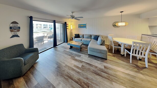 A modern living room with a sofa, a coffee table, and a dining area with chairs. - La Buena Vida by Miss Kitty’s (Rockport)