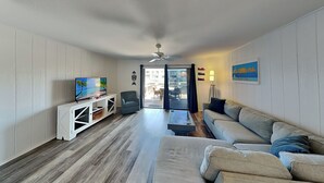 A living room with a TV, sofa, and a view of the outside. - La Buena Vida by Miss Kitty’s (Rockport)