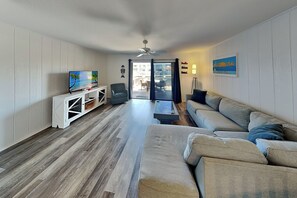 A living room with a TV, sofa, and a view of the outside.