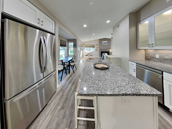 A modern kitchen with stainless steel appliances, a granite countertop, and a dining area with a table and chairs.