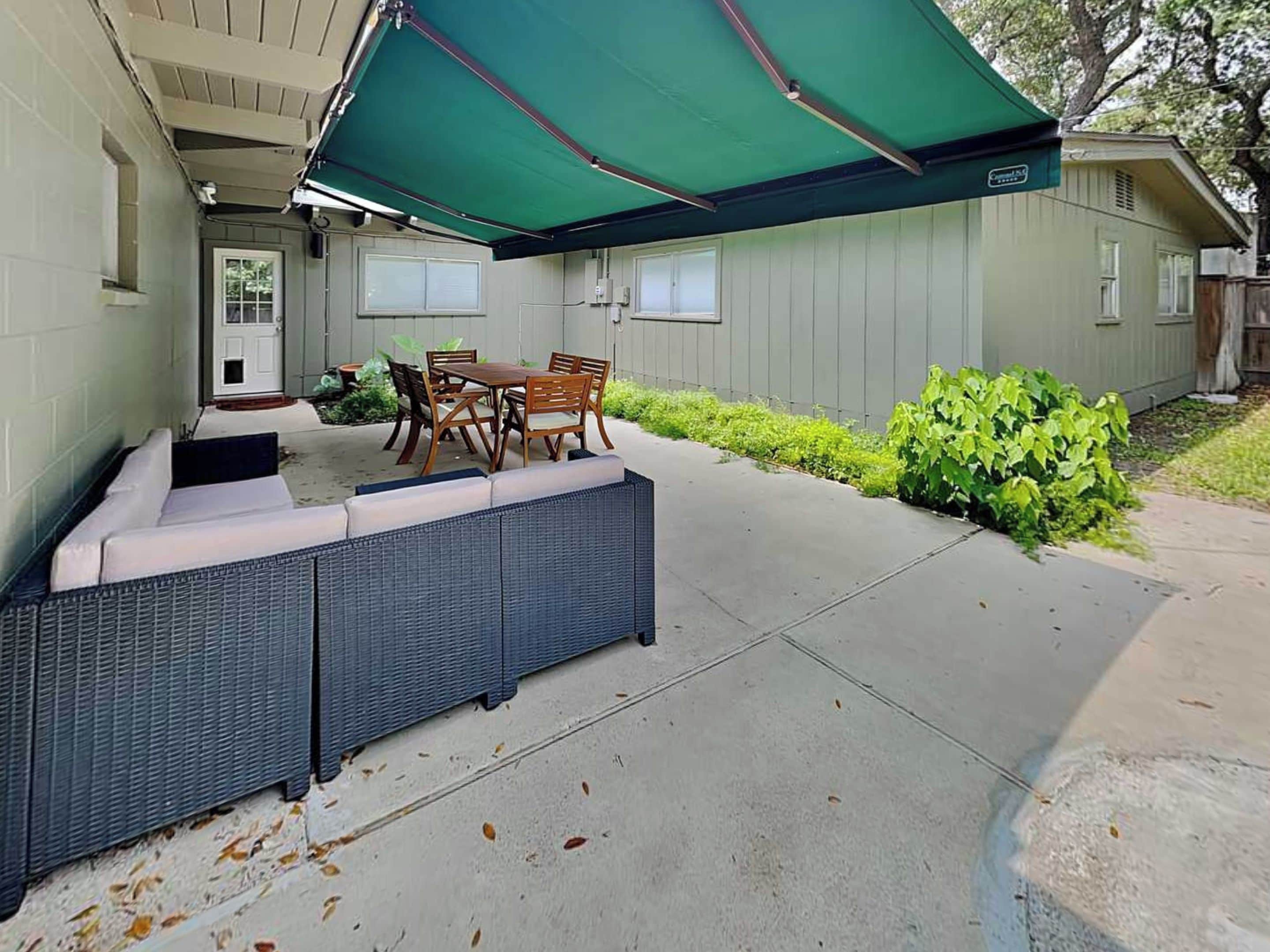 An outdoor patio with a covered seating area, a table, and chairs.