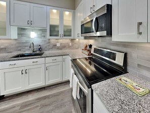 Una cocina moderna con armarios blancos, horno de acero inoxidable y microondas.