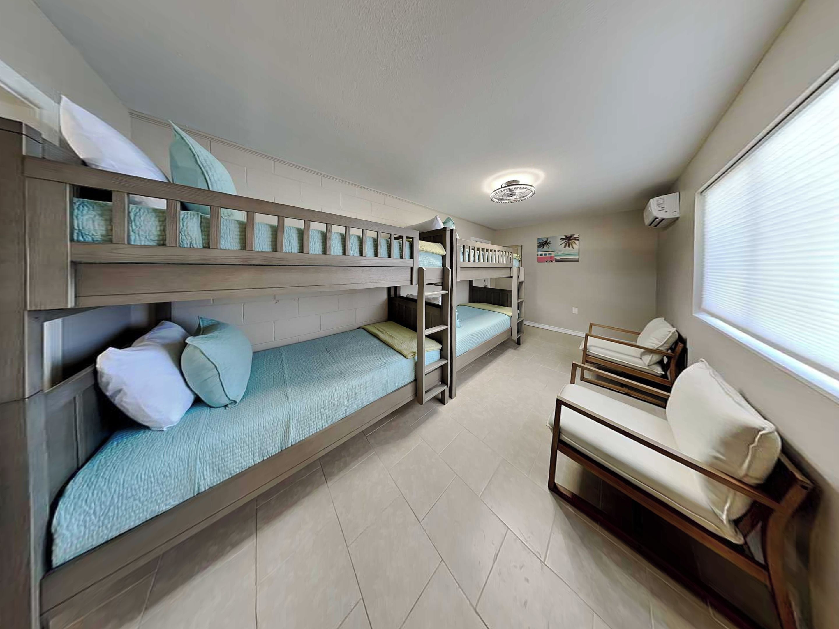 Habitación con literas, un escritorio, una silla, una ventana y una lámpara en el techo.