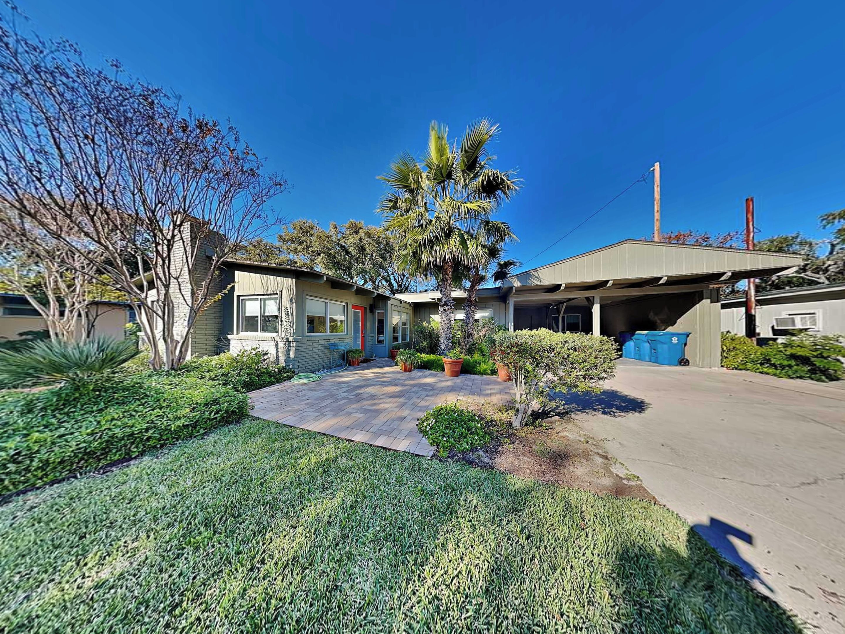 A residential property with a garage, a well-maintained lawn, and a variety of plants.