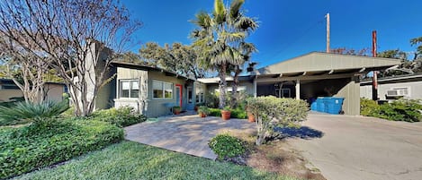 A residential property with a garage, a well-maintained lawn, and a variety of potted plants.