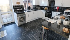 A modern kitchen with a washing machine, a stove, and a sink. - The Old Well Bungalow - Ty Mawr Farm (Cardiff)