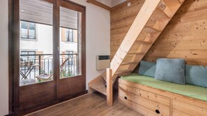 A wooden staircase leading to a loft bedroom with a green sofa and pillows. - A lovely flat right in the centre of Chamonix (Chamonix-Mont-Blanc)