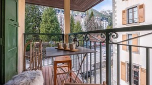 A balcony with a table and chairs, a fur-covered bench, and a view of buildings and trees. - A lovely flat right in the centre of Chamonix (Chamonix-Mont-Blanc)