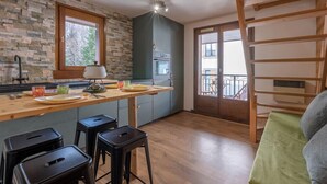 A kitchen with a stone wall, wooden counter, and a view of the outside balcony. - A lovely flat right in the centre of Chamonix (Chamonix-Mont-Blanc)