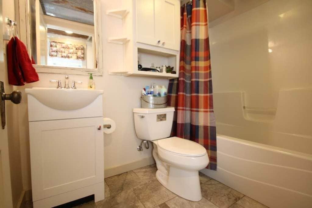 Un baño con lavamanos, inodoro y cortina de ducha blancos.
