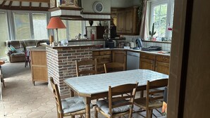 Cucina spaziosa con isola centrale, mobili in legno e zona pranzo con pavimento in piastrelle esagonali.
