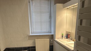 Un bagno moderno con una vasca, un lavandino e una finestra con persiane.