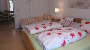 A bedroom with a bed, pillows, a bedside table with a lamp, a wall decoration, and a view of a dining area. - Herrlich an Wald u. Wiesenrand,ruhige Lage. Erdgeschoss, Terrasse ,fam. mit Kind (Berghaupten)