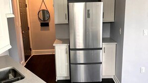 A kitchen with a stainless steel refrigerator, white cabinets, and a speckled countertop. - Lovely 1 bedroom apartment

 (Livingston)