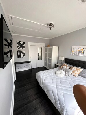 Un dormitorio moderno con una cama grande, un armario, un escritorio y un ventilador de techo.