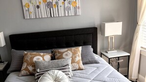 A neatly made bed with a quilted grey duvet, multiple pillows, and a decorative pillow with a white and grey pattern. - Lovely 1 bedroom apartment

 (Livingston)