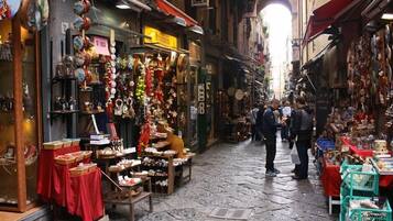 A narrow street with shops on both sides, displaying various goods.
