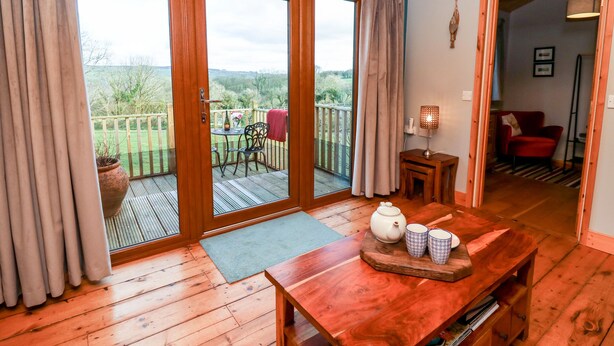A wooden-floored room with a sliding glass door leading to a balcony. - Y Caban Glas (Llandysul)
