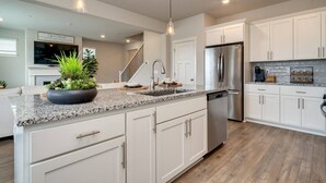 A modern kitchen with white cabinetry, granite countertops, stainless steel appliances, and pendant lighting. - Relaxing Getaway w/ Pool Access!

 (Camas)