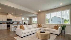 A modern living room with a sectional sofa, a round coffee table, and a kitchen in the background. - Relaxing Getaway w/ Pool Access!

 (Camas)