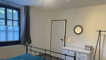 A bedroom with a bed, a dresser, a mirror, and a radiator.