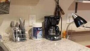 Een compacte keuken met een granieten aanrecht, een koffiezetapparaat en een vaatwasser.