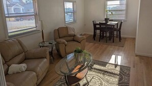 A living room with a sofa, a glass coffee table, and a dining area with a table and chairs. - Nestled in the heart of Pierre, shopping & dining near. (Pierre)