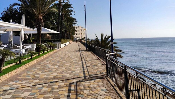 A seaside promenade with outdoor seating, palm trees, and a view of the sea. - Caballito del Mar apartment in Punto Prima, Valencia (Punta Prima)
