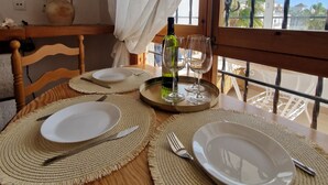A dining table set with plates, cutlery, and a bottle, with a view of palm trees and a clear sky through large windows. - Caballito del Mar apartment in Punto Prima, Valencia (Punta Prima)