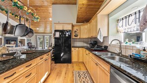 Una cocina con armarios de madera, un refrigerador negro, encimeras de granito y decoración con motivos de café.
