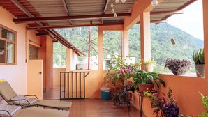 A balcony with wooden flooring, potted plants, and lounge chairs. - Cozy Apartment for 2 w/roof. View to Volcanoes (Panajachel)