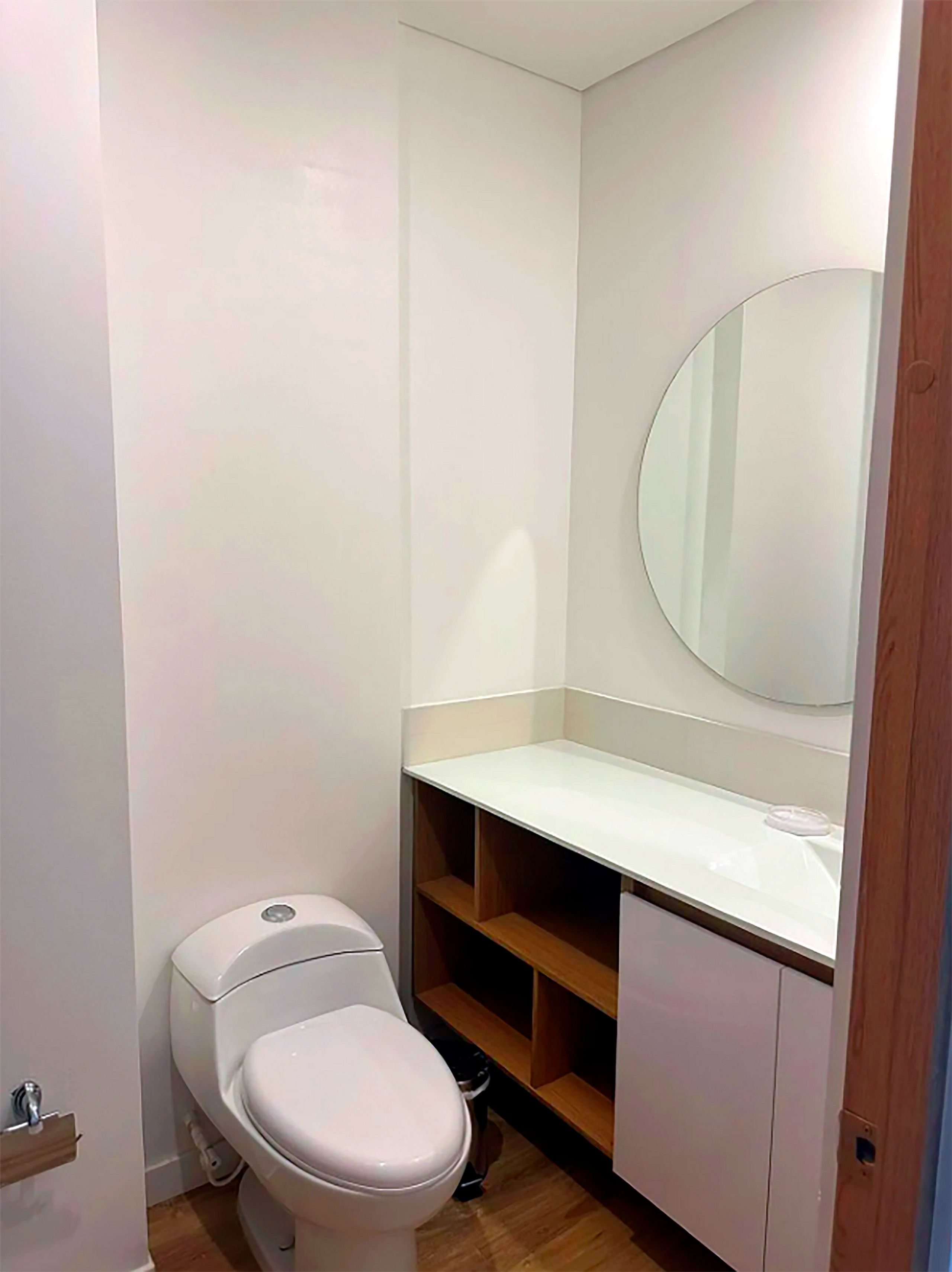 A small, compact bathroom with a toilet, a sink, and a mirror.