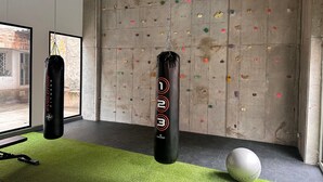 A gym with a climbing wall, two punching bags, and a yoga ball. - U-GO Edificio Next Living Bogota (Bogotá)