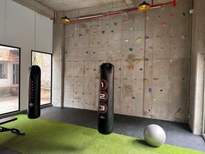 Une salle de sport équipée d’un mur d’escalade, de deux sacs de frappe et d’un ballon de yoga.
