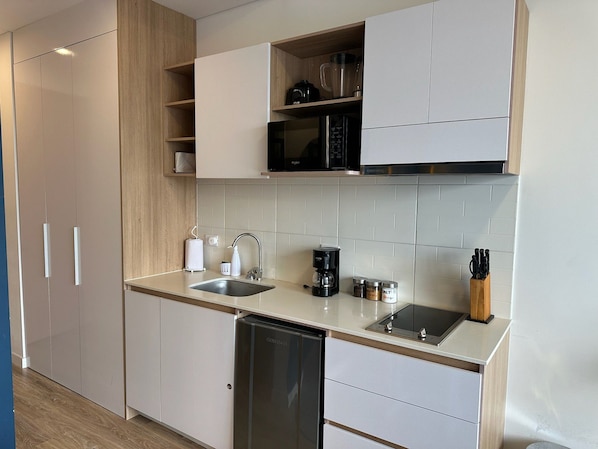 A modern kitchen with a dishwasher, a coffee maker, and a microwave.
