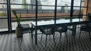 A conference room with a glass table and chairs, large windows with a city view, and a potted plant. - U-GO Edificio Next Living Bogota (Bogotá)