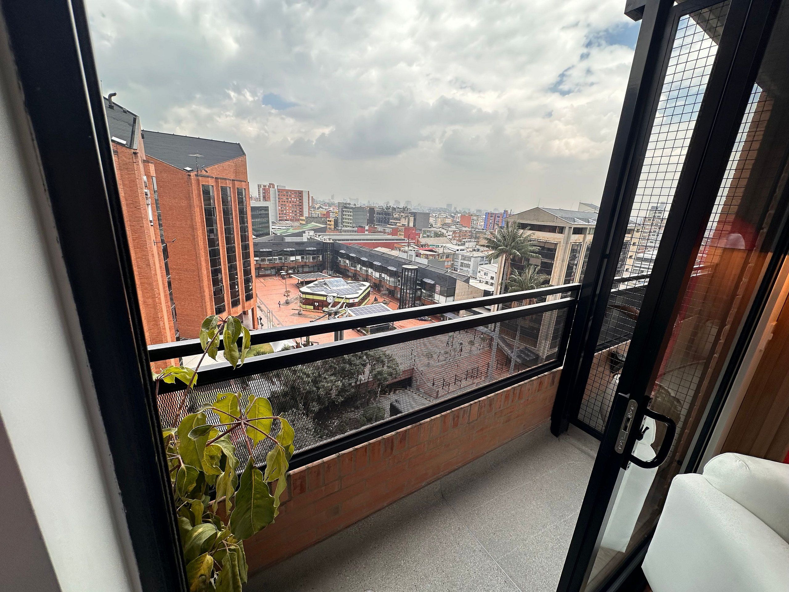 Een balkon met uitzicht op een stadsgezicht, met gebouwen en een palmboom.