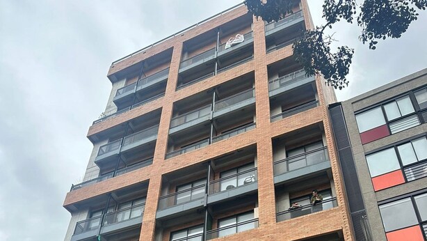 A multi-story building with balconies, a garage entrance, and a sign indicating availability. - U-GO Edificio Next Living Bogota (Bogotá)