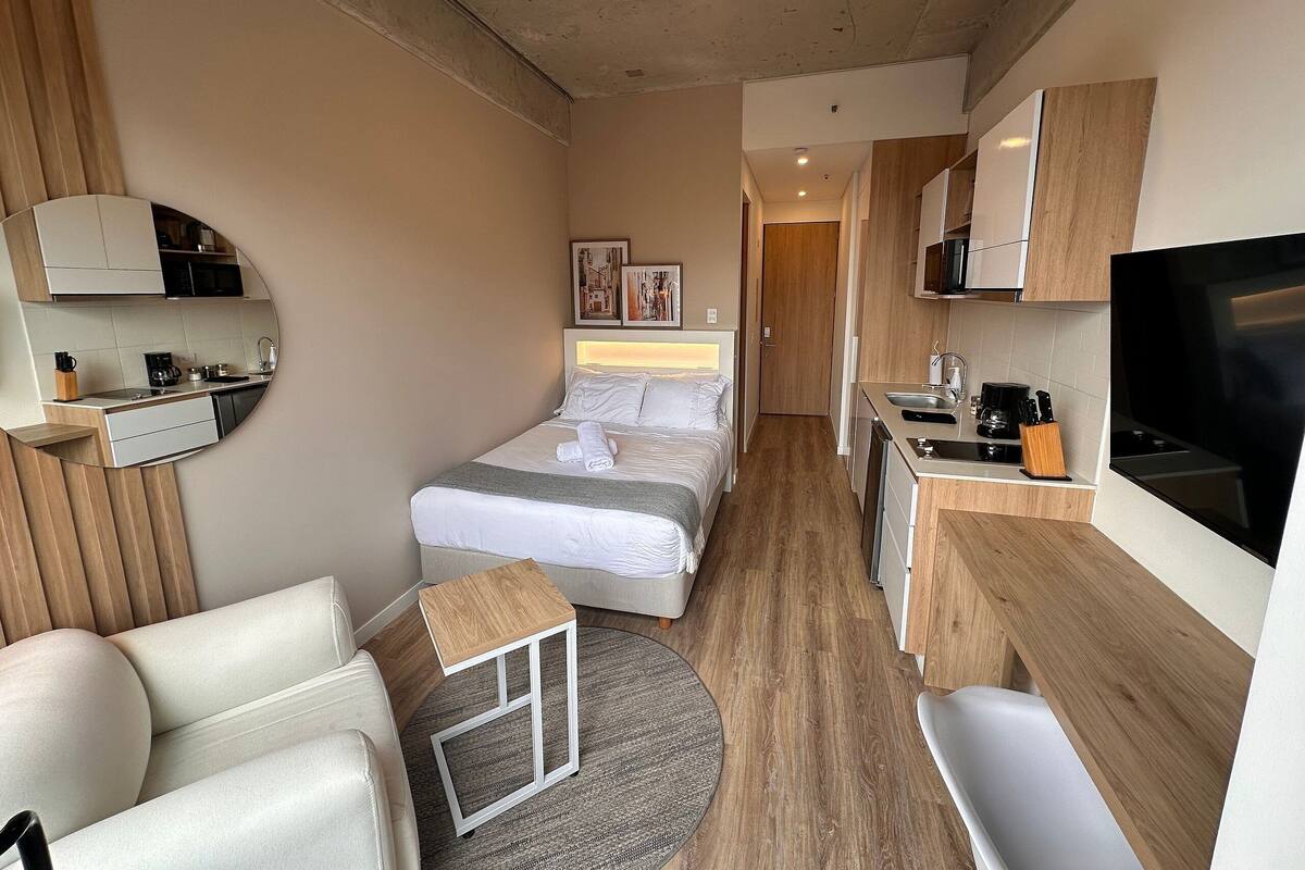 Une chambre d’hôtel compacte comprenant un lit, une petite kitchenette, un coin salon et un téléviseur.