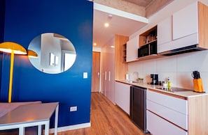 A modern kitchen with wooden cabinets, a built-in microwave, and a coffee maker. - U-GO Edificio Next Living Bogota (Bogotá)