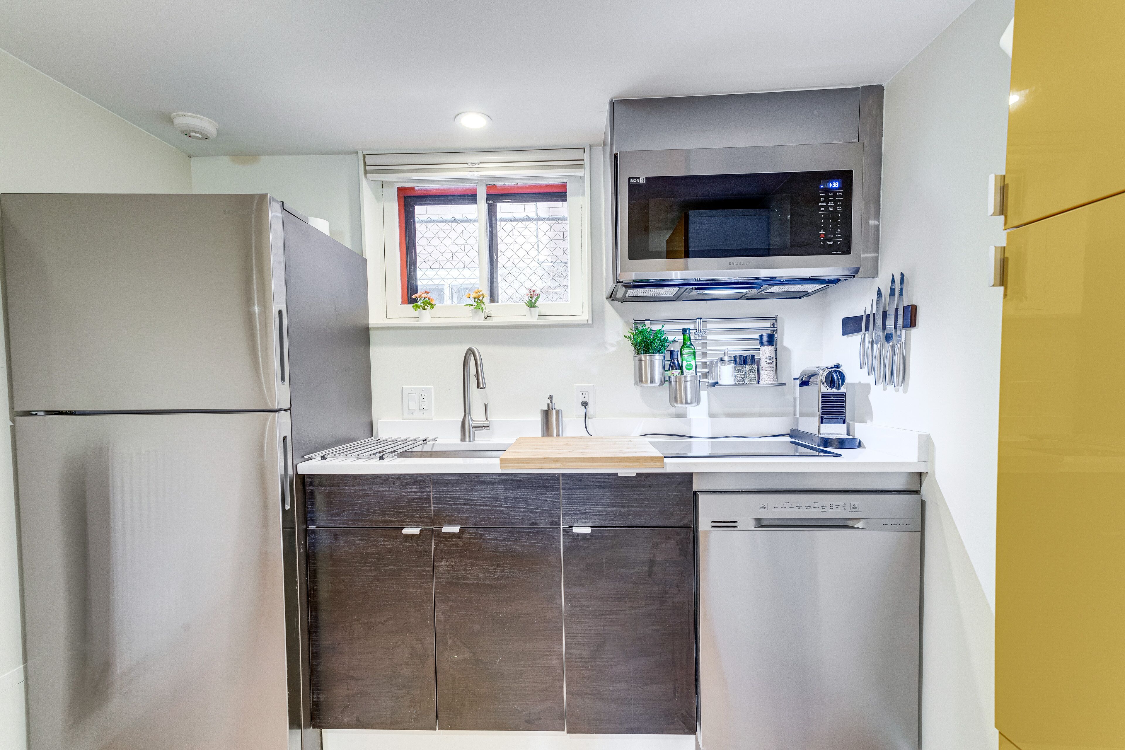 Una cocina moderna con un refrigerador de acero inoxidable, un microondas, un lavavajillas y una ventana con vistas a la ciudad.