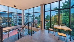Ein geräumiges Zimmer mit großen Fenstern und Blick auf Stadt und Grünflächen.