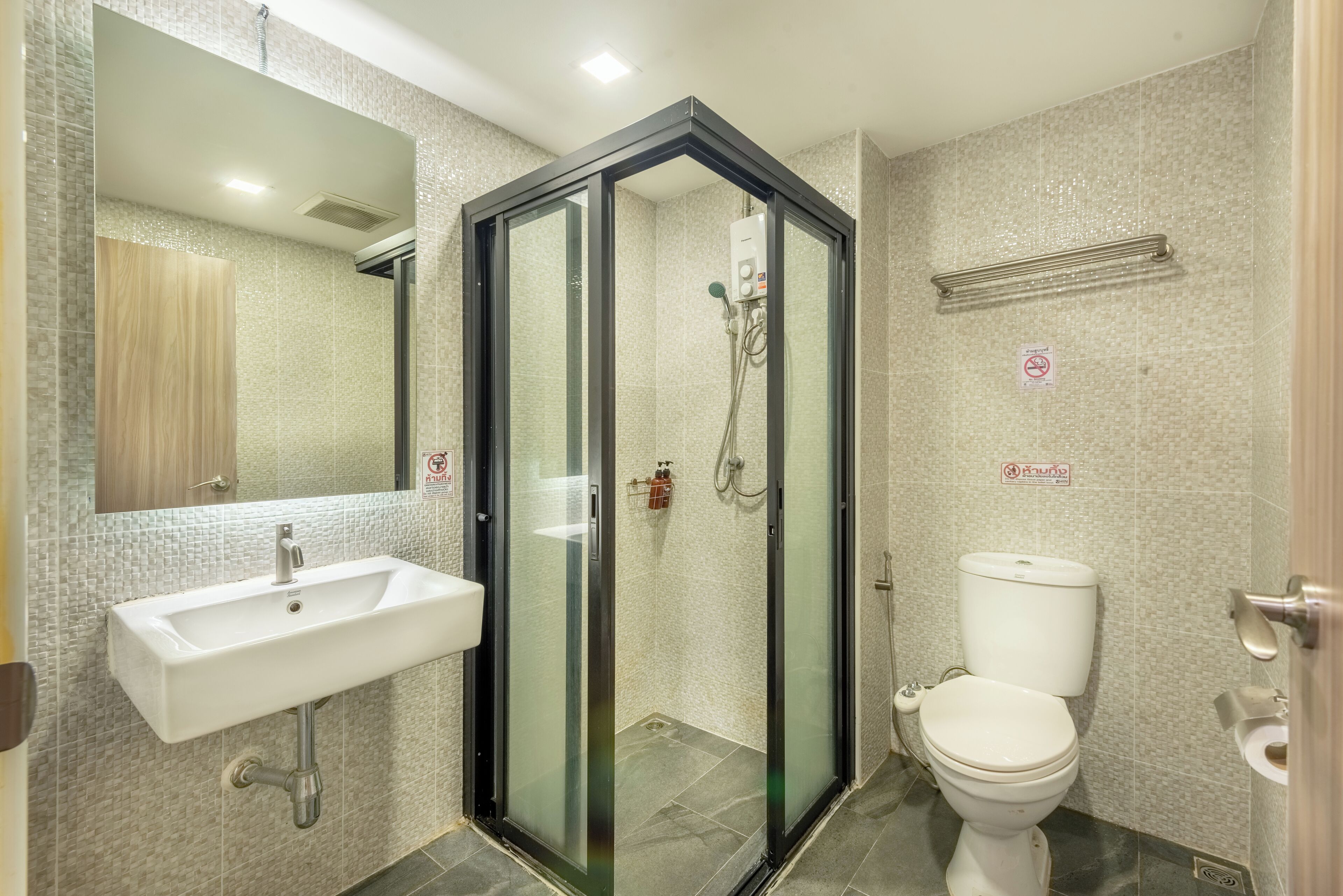 A bathroom with a glass-enclosed shower, a sink, and a toilet.