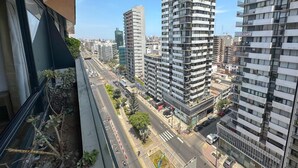A high-rise building with multiple balconies, a clear sky, and a busy street with cars and pedestrians. - Exclusive Apartment Just Steps from San Isidro (Lince)