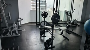 A modern gym with various exercise equipment, large windows, and a view of a cityscape. - Exclusive Apartment Just Steps from San Isidro (Lince)