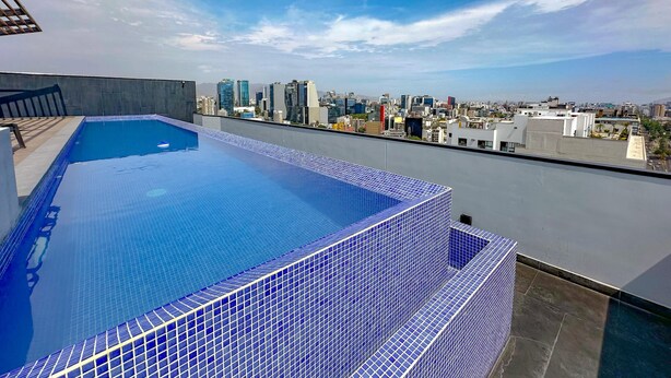 A rooftop pool with a cityscape view. - Exclusive Apartment Just Steps from San Isidro (Lince)