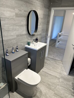 Een moderne badkamer met toilet, wastafel en kastjes.