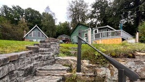 Eine rustikale Steintreppe führt zu einem hölzernen Deck mit Metallgeländer.